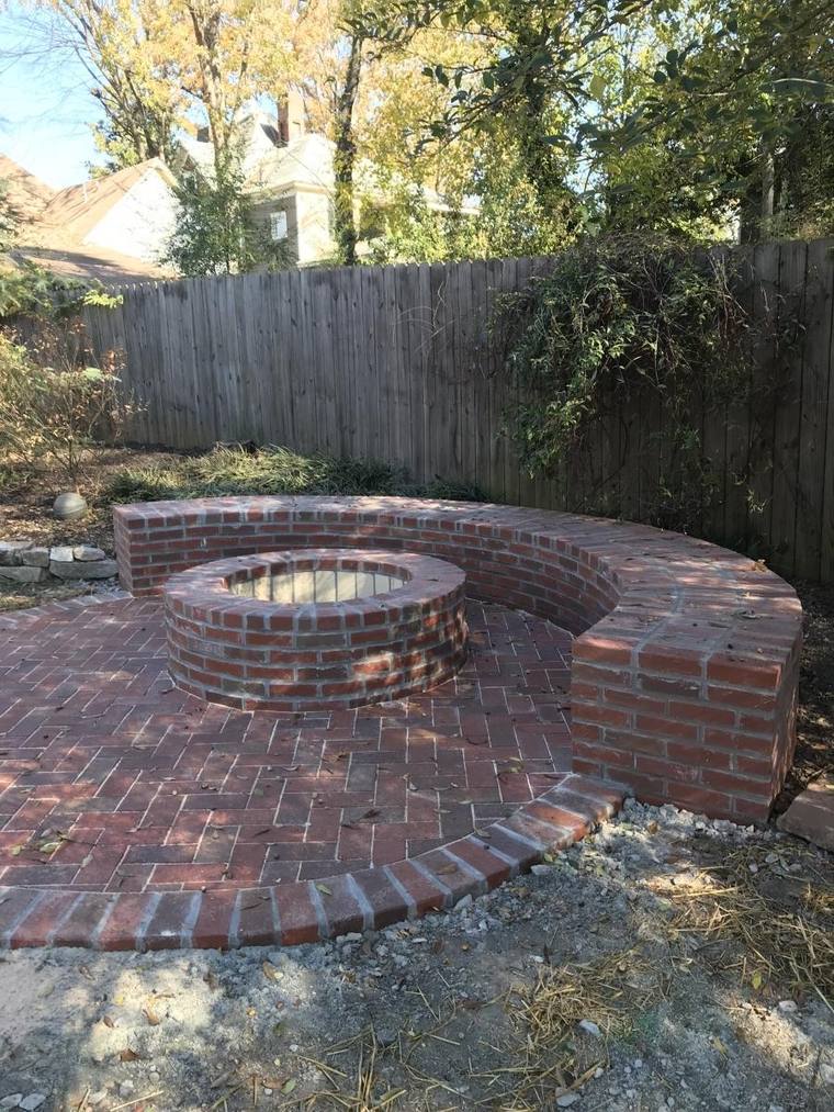 Wood burning brick fire pit with a curved masonry seating bench and back wall