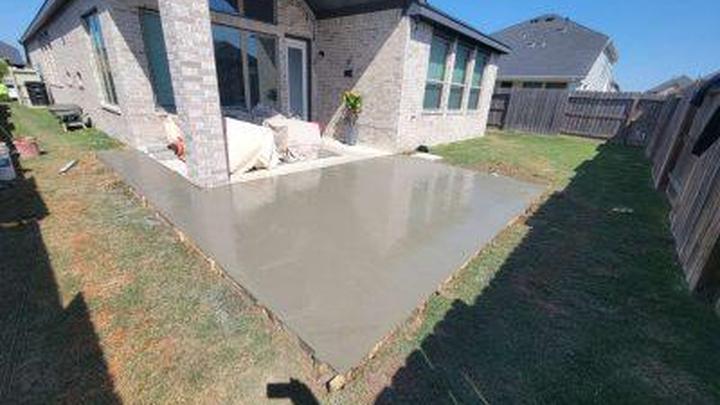 Freshly poured and floated reinforced concrete patio slab against a brick house in Louisiana