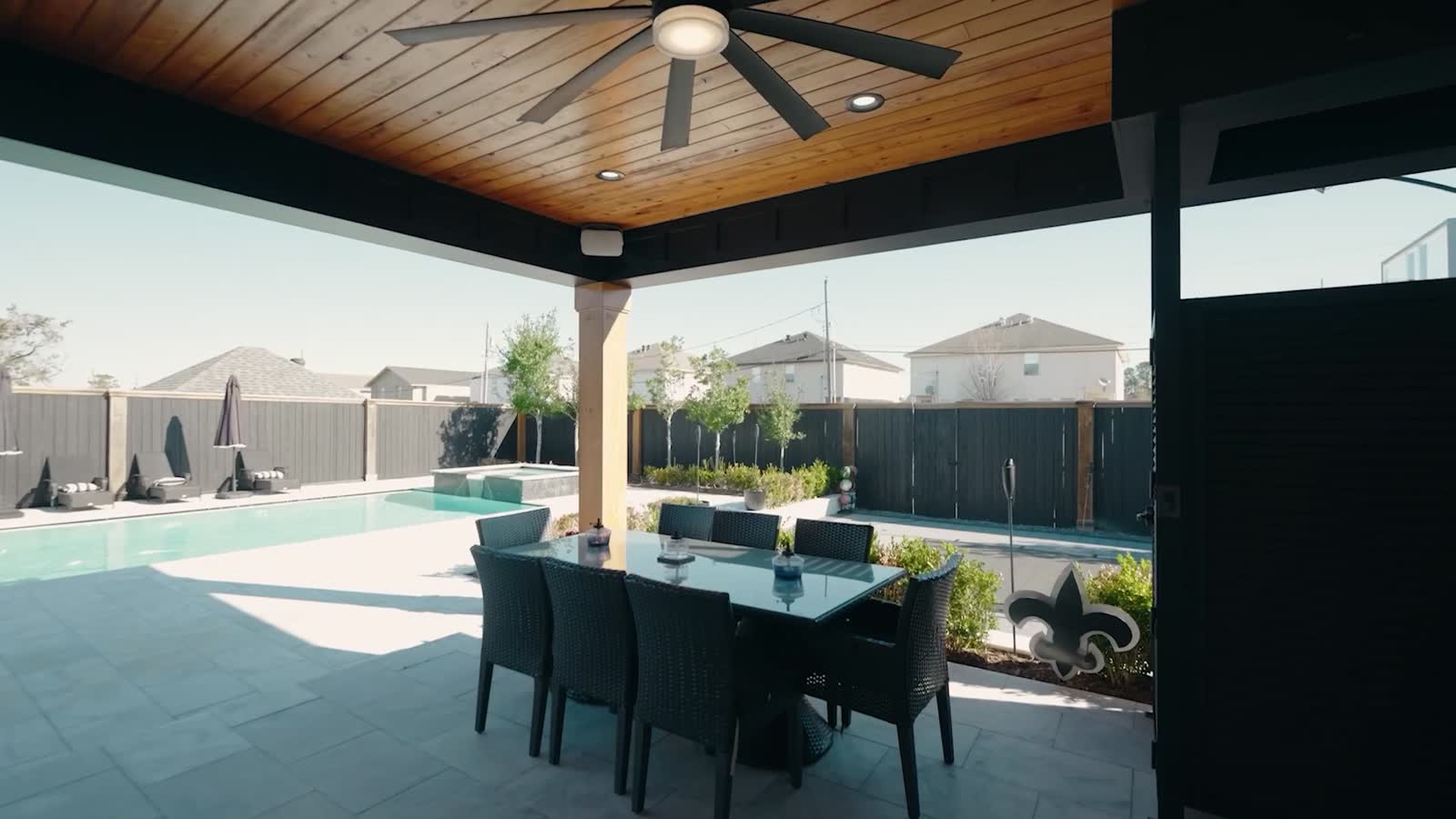 Covered patio with a stained cypress ceiling and fan looking out over paver decking