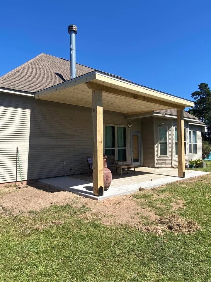 Attached shed roof patio cover on wood posts over a new concrete slab at the back of a house